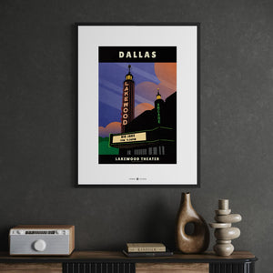 A framed travel poster of the Dallas Lakewood Theater hanging on a dark gray wall above a console table with decorative objects.