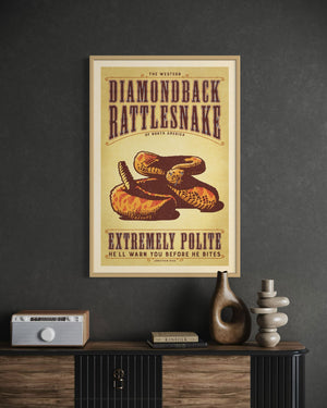 Oak framed poster of a diamondback rattlesnake on a dark wall above a wooden cabinet.