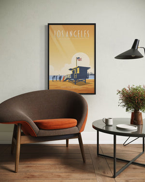 Los Angeles Santa Monica State Beach poster displayed above a mid-century modern chair, featuring a lifeguard tower and warm coastal sunset tones.