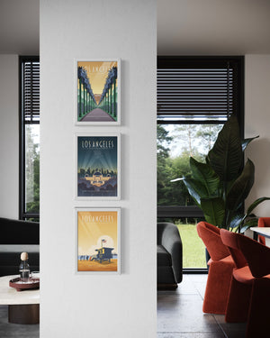 4. Vertical gallery wall of three Los Angeles travel posters framed in white, displayed in a modern living space.