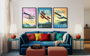 Mid century aviation wall art set of three in black frames above a sofa featuring vintage Seattle, Big Bend, and Catalina Island airplane posters