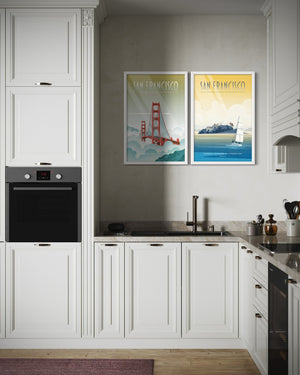 Framed San Francisco travel posters of the Golden Gate Bridge and Alcatraz displayed as a coordinated gallery set above a kitchen counter