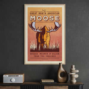 Oak framed moose wildlife print with warm natural wood tones that complement the earthy colors of the vintage animal illustration featured in an office environment.