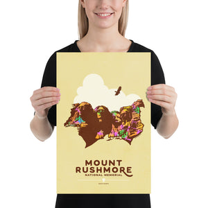 Product mockup of Minimalist giclée art print of Mount Rushmore with four U.S. Presidents and an eagle overhead. Text at the bottom reads "Mount Rushmore National Memorial, South Dakota." Bold colors against a muted background.