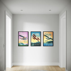 Three framed posters of vintage airplanes on a wall in a room with wooden flooring.