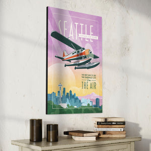 Retro style giclée art print of a De Havilland Canada DHC-2 Beaver floatplane flying over Seattle, Washington.. It has the words “Seattle Vintage Air Tours” at the top. The print’s soft purples, yellows, blues and greens create a stunning backdrop for the classic floatplane with it’s touch of red. There are additional words a the bottom that says “The best way to see the Emerald City is from the air.”