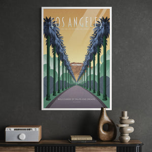 A framed Los Angeles travel poster hanging on a dark gray wall above a console table with decorative objects. The poster features a retro-style illustration of palm trees lining a road toward the Hollywood sign, with the words 'LOS ANGELES' and 'Boulevards of palms and dreams.