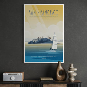 A framed travel poster of San Francisco hanging on a dark gray wall above a console table with decorative objects, featuring a vintage-style illustration of a sailboat on blue water under a yellow sky.