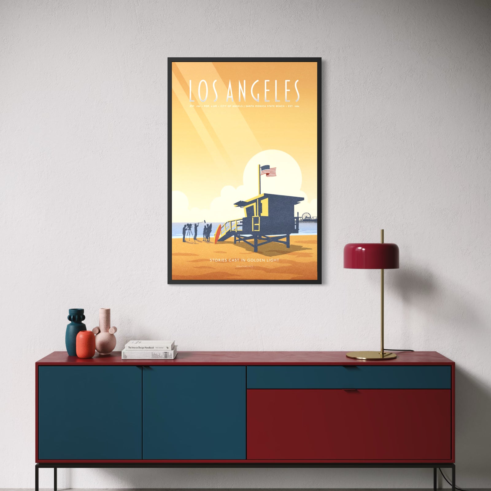 A stylized Los Angeles travel poster print featuring a beach scene with a lifeguard tower, ocean, sun, and the text 'LOS ANGELES' and 'STORIES CAST IN GOLDEN LIGHT'.