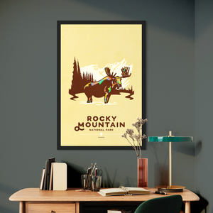 Modern, minimalist giclée art print for Rocky Mountain  National Park in South Dakota. This simple and classy poster depicts a moose standing in a lake with forest and mountains in the background.  It has the words “Rocky Mountain National Park, Colorado”  at the bottom. 