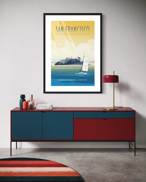 Framed San Francisco Alcatraz poster hanging above a red and blue mid-century modern credenza with decorative objects.