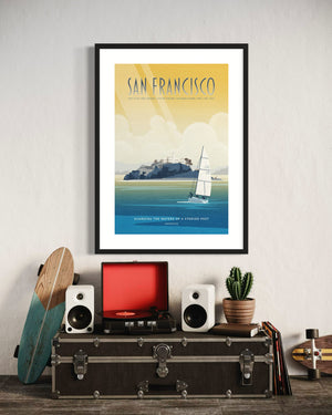 Framed San Francisco Alcatraz poster hanging above a vintage-style record player, speakers, and decorative items including a cactus and skateboard.