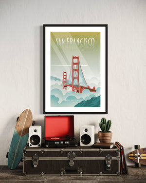 Framed San Francisco Golden Gate Bridge poster hanging above a vintage-style setup featuring a record player, speakers, a cactus plant, and wooden skateboards leaning against a wall.