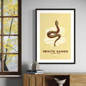 Modern, minimalist giclée art print of White Sands National Park & Preserve in Alaska. This simple and classy poster depicts a Diamondback Rattlesnake slithering across the white sands of the park. It has the words “White Sands National Park, New Mexico”  at the bottom. The print’s muted overall background color allows the bold and vibrant colors of the main image to pop. 