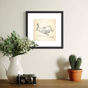Framed Running Rabbit sketch above cabinet with vase, camera and cactus
