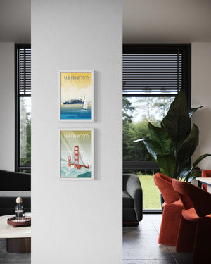 Vertical gallery display of framed San Francisco travel posters featuring the Golden Gate Bridge and Alcatraz mounted on a wall pillar