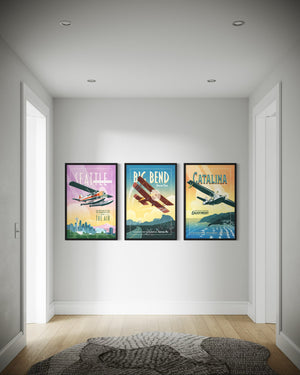 Vintage aviation poster set of three in black wood frames displayed in a modern hallway featuring Seattle seaplane, Big Bend biplane, and Catalina Island retro travel wall art