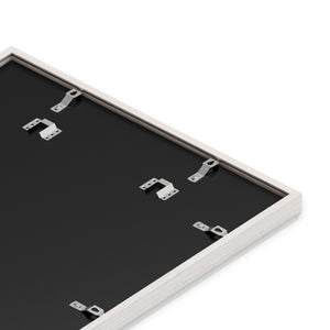 Back of framed picture showing metal clips and saw tooth hangers on a black backer board.