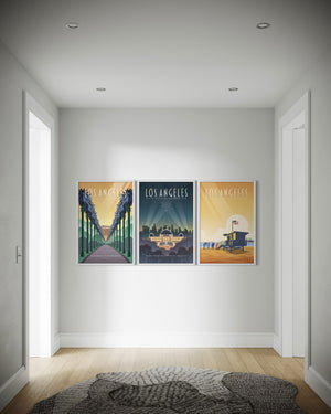 Los Angeles gallery wall set of three framed travel posters displayed in a hallway, featuring Hollywood palms, Griffith Observatory, and Santa Monica Beach