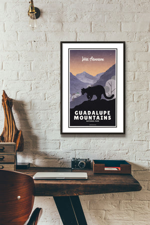 A retro style giclée art print of a mountain lion in Guadalupe Mountains National Park in Texas. It has the words “Wild Adventure” at the top. The print primarily is in bold navy blue with bright sunset colors. There are additional words a the bottom that says “Guadalupe Mountains National Park”.
