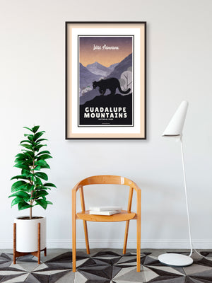 A retro style giclée art print of a mountain lion in Guadalupe Mountains National Park in Texas. It has the words “Wild Adventure” at the top. The print primarily is in bold navy blue with bright sunset colors. There are additional words a the bottom that says “Guadalupe Mountains National Park”.