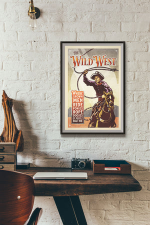 Bold graphic giclée art print of a Cowboy riding a horse and swinging a rope with the words “The Wild West”. Print is an ink portrait, with color, and a sky background with sun rays.